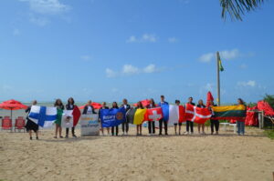 schüleraustausch 2027/2028 mit Rotary. Schüler mit Flaggen in Brasilien am Strand. 